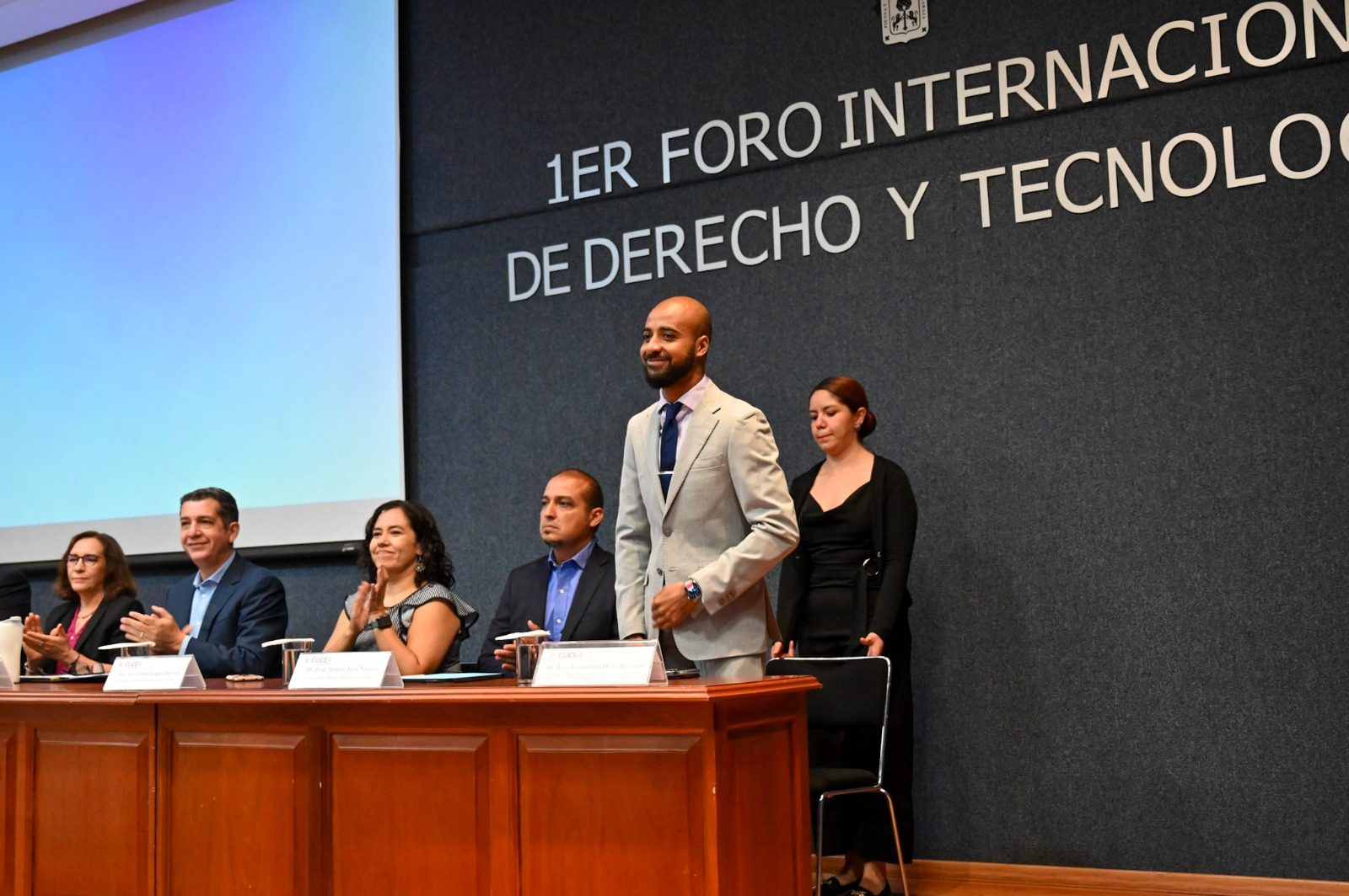 Presentación de ponente internacional con la mesa de panelistas y letrero institucional